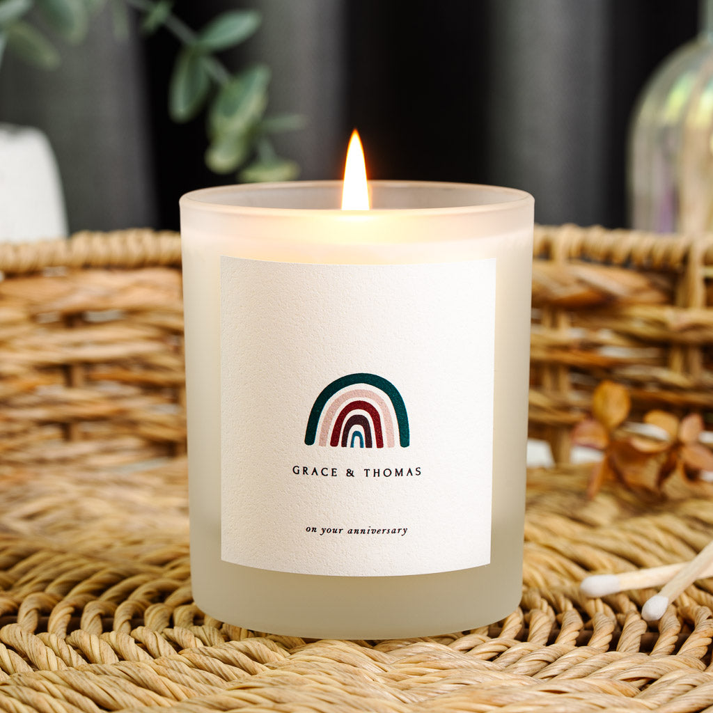 Personalised anniversary candle with a rainbow motif above the names in bold capitals