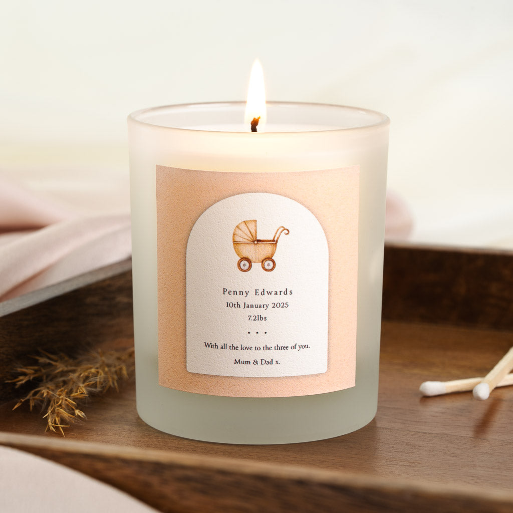 Personalised new baby candle with a vintage pram illustration inside a peach-toned arch