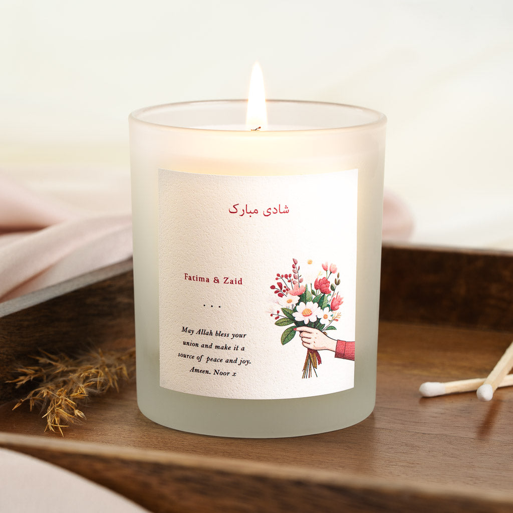 Personalised nikah candle with a hand holding pink and white blooms beneath red script