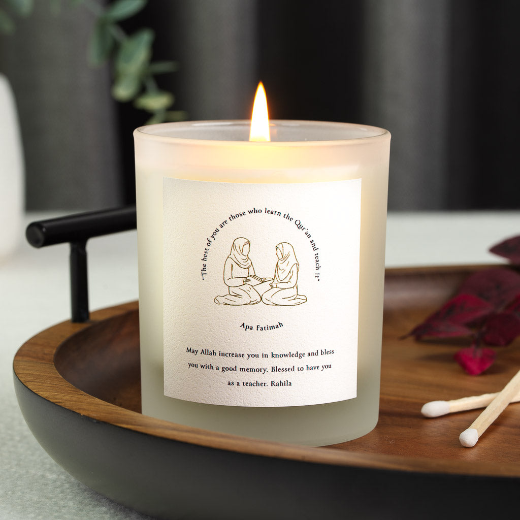 Two seated figures with an open book beneath a hadith on a personalised Quran teacher candle