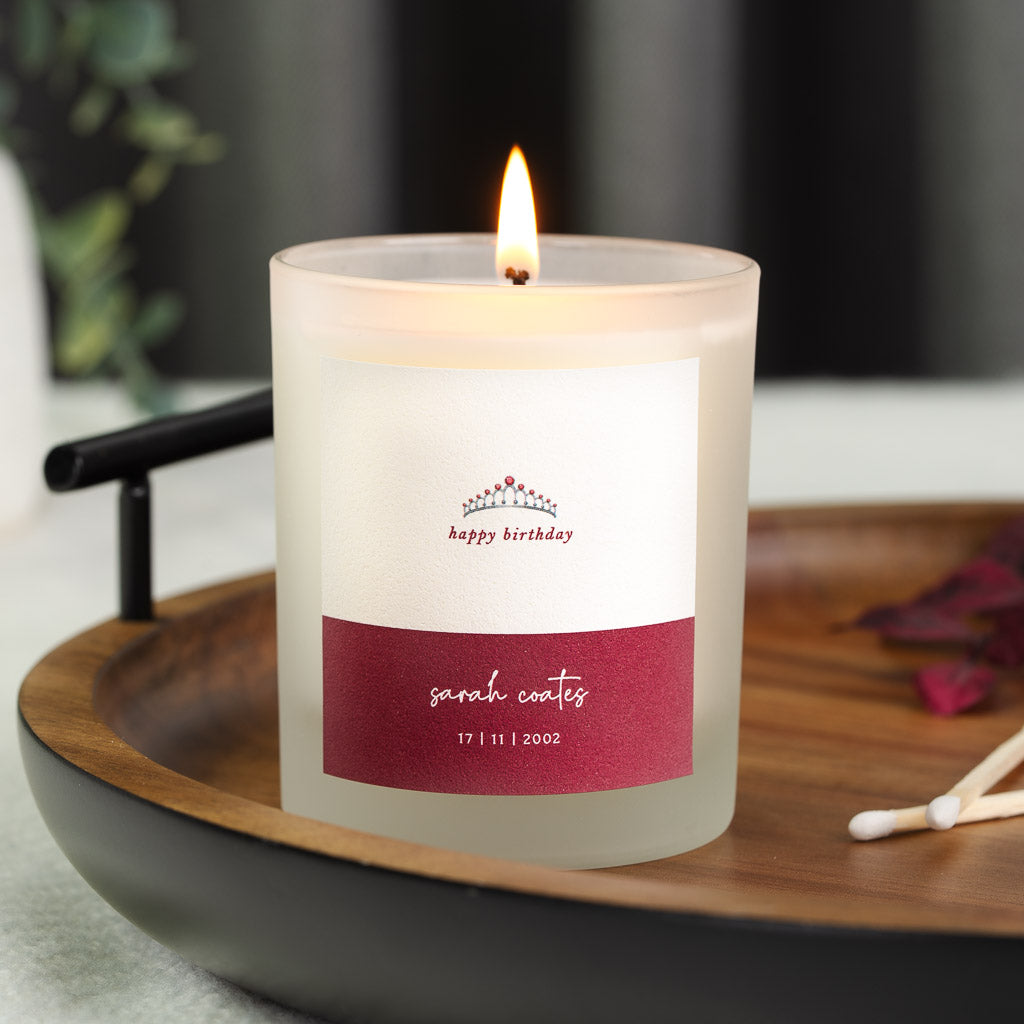 Tiara illustration on soft white above a burgundy name panel on a personalised candle
