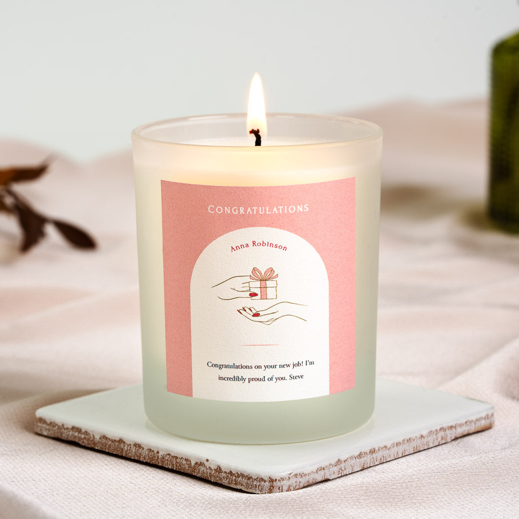 Illustrated hand offering a wrapped gift on a soft pink personalised congratulations candle
