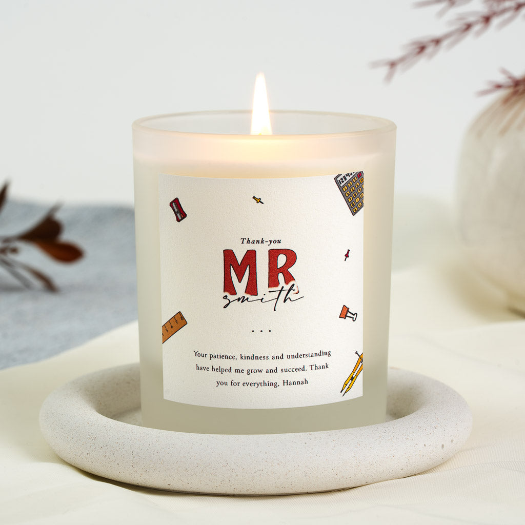 Rulers, pins and a calculator scattered around bold lettering on a personalised teacher candle