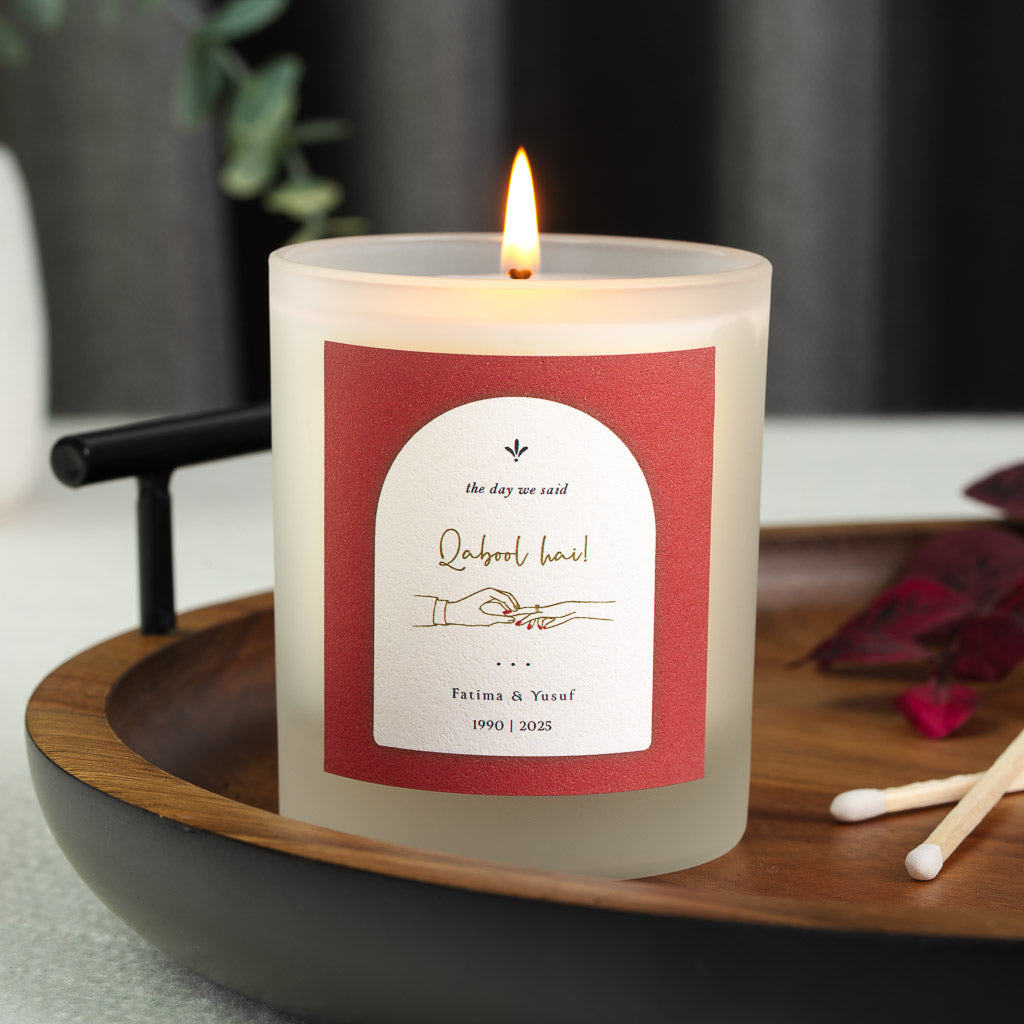 Personalised anniversary candle with a ring being placed on a hand inside a deep red arch