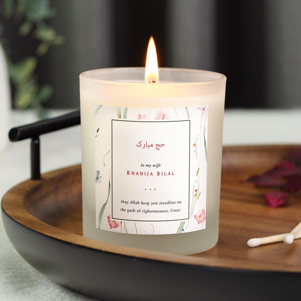 Personalised Hajj candle with a floral border framing a boxed Arabic greeting panel