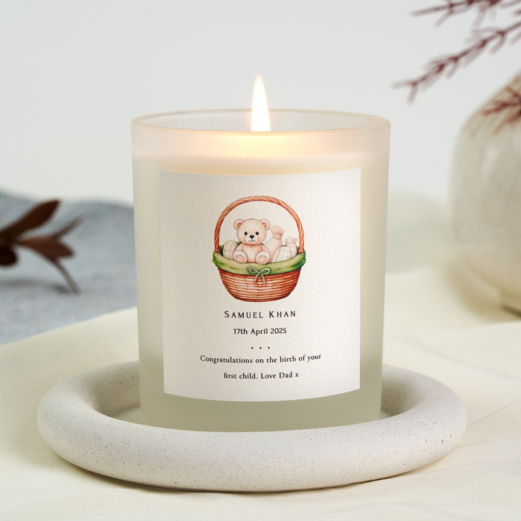 Personalised new baby candle with a bear sitting in a wicker basket tied with a green bow