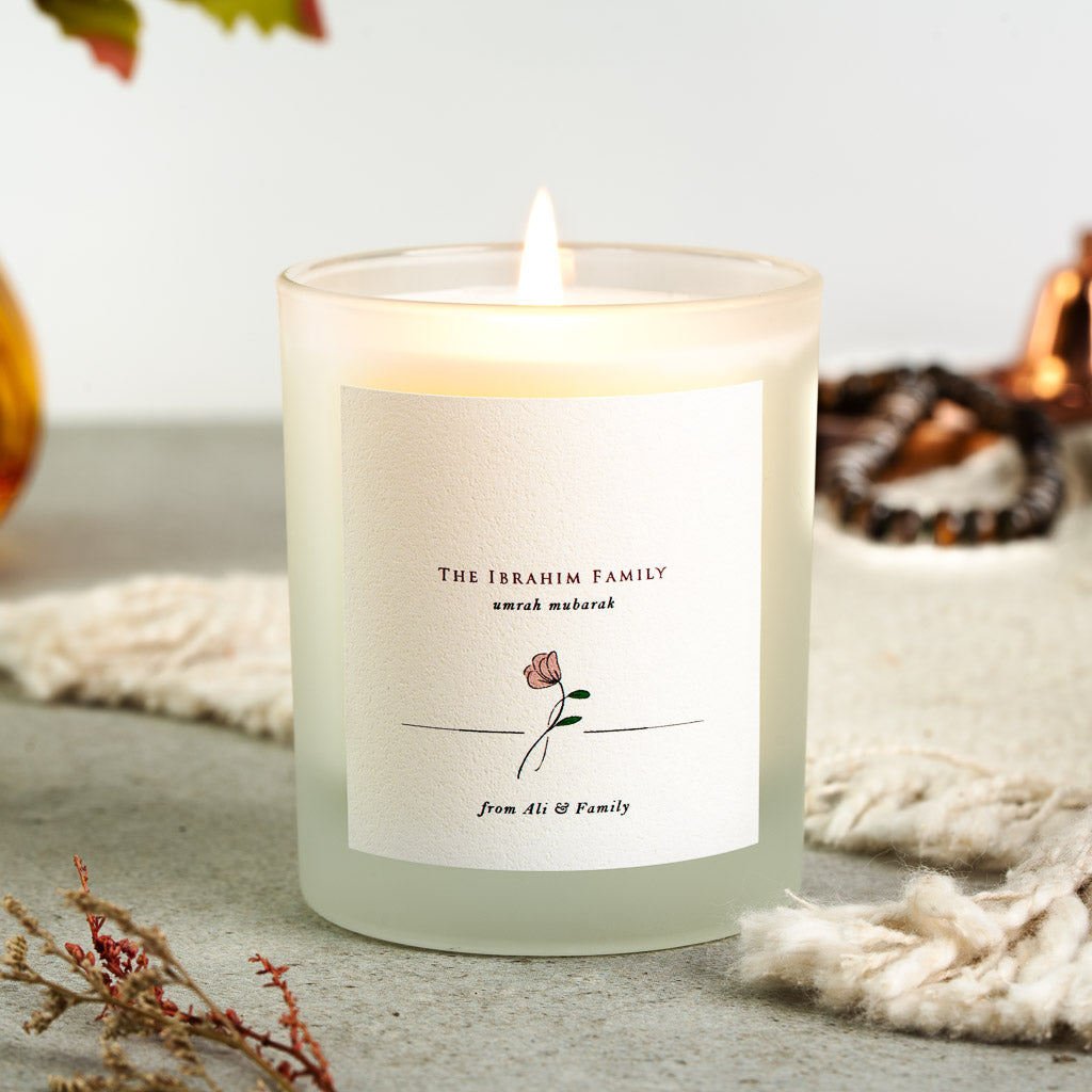 Family name above the greeting in plain serif on a personalised Umrah candle label