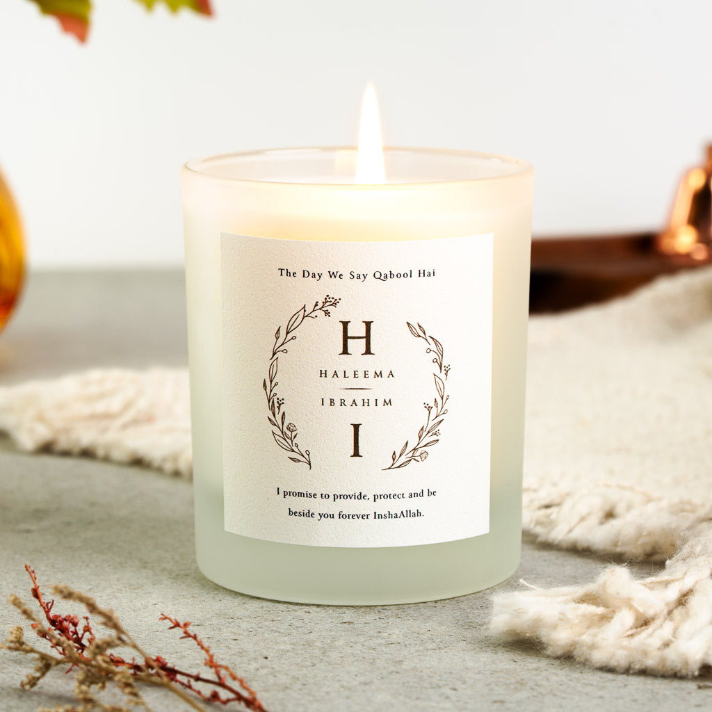 Pressed botanical wreath framing a large initial on each side of a personalised nikah candle