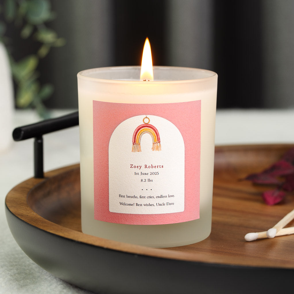Personalised new baby candle with a woven rainbow charm inside a white arch on dusky pink