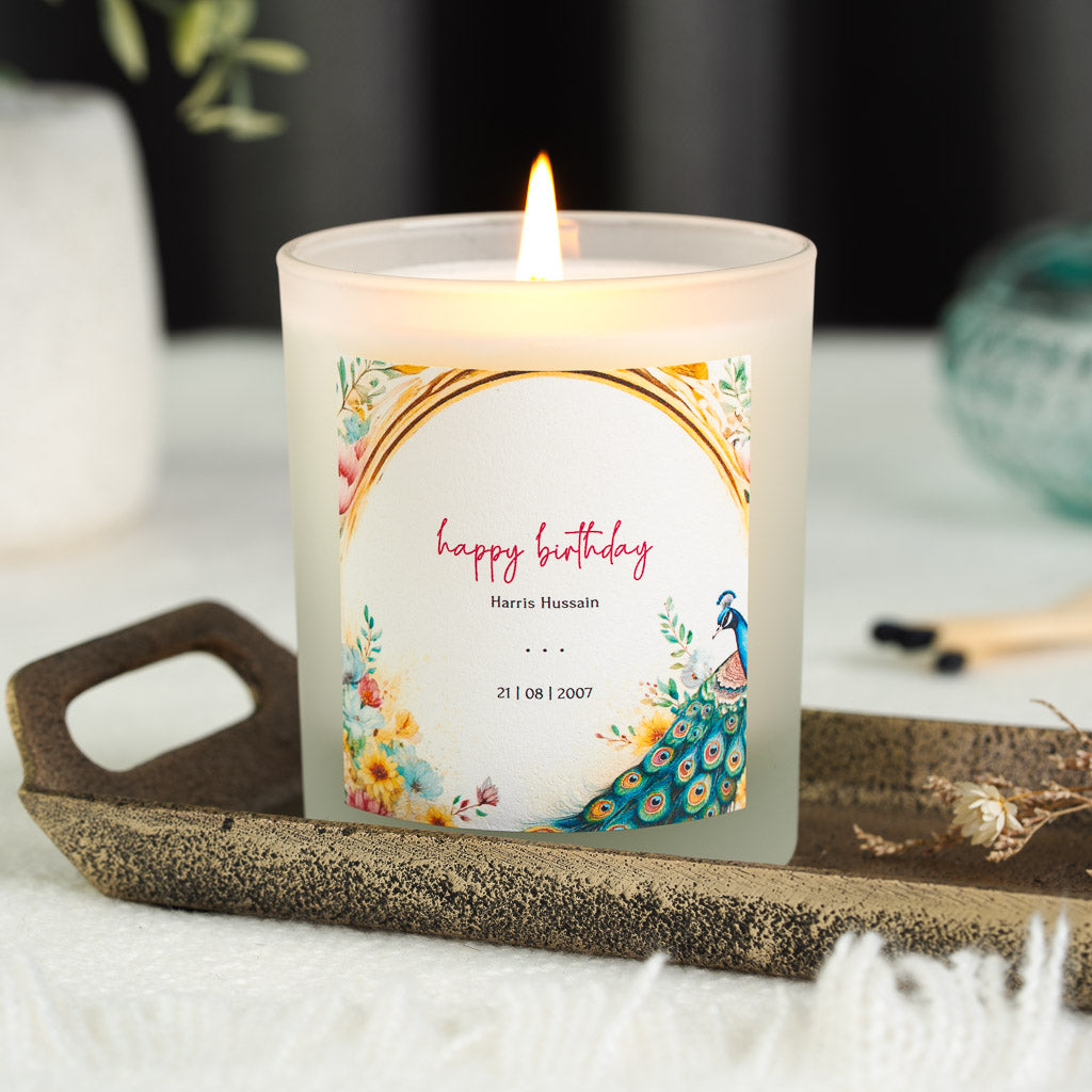 Watercolour flowers and a peacock tail bordering an arch on a personalised birthday candle
