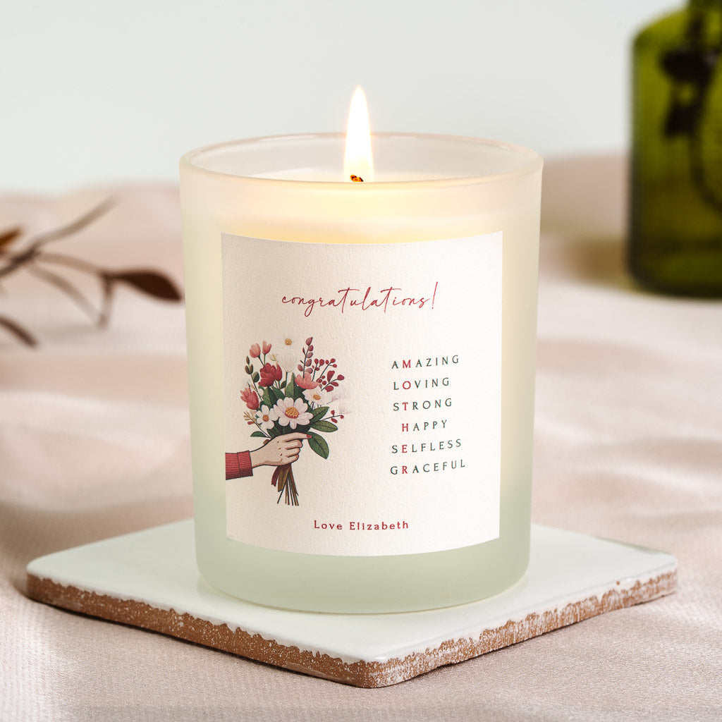 Personalised new baby candle with a hand holding a red and white bouquet beside red script