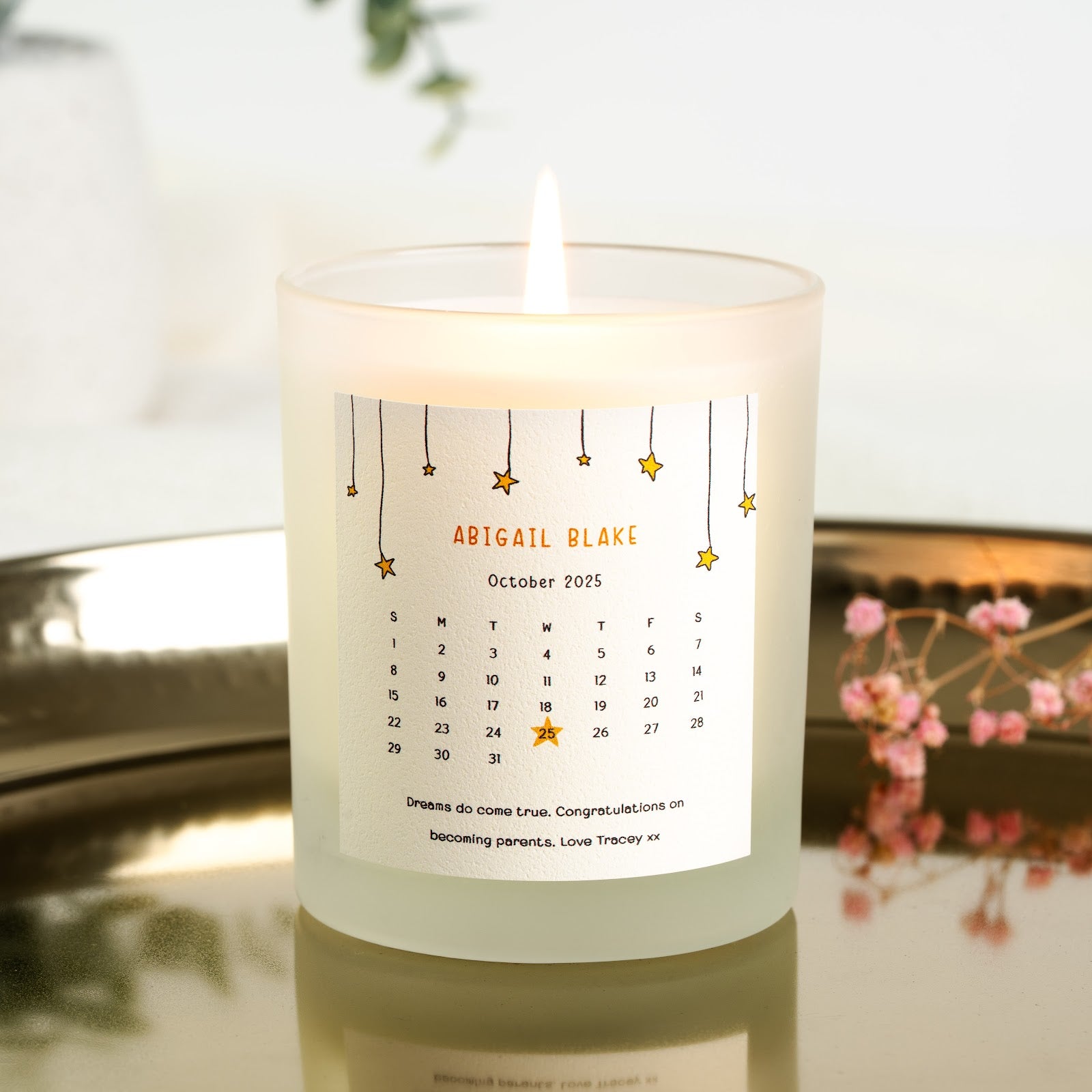 Small hanging stars bordering a birth month calendar on a personalised new baby candle