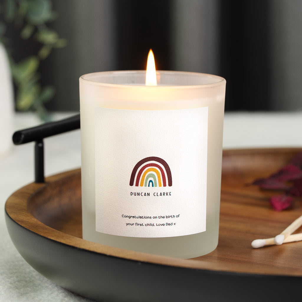 Personalised new baby candle with a deep red, gold and teal rainbow above the name