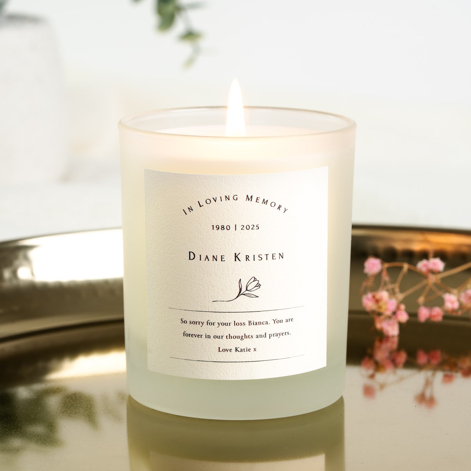 Personalised memorial candle with a flower illustration beneath the name and dates