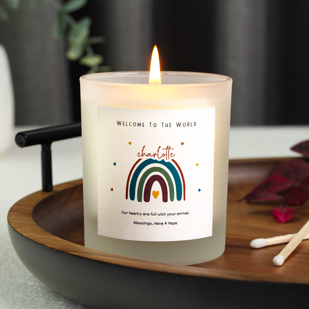 Deep red and teal rainbow above the name in red script on a personalised new baby candle