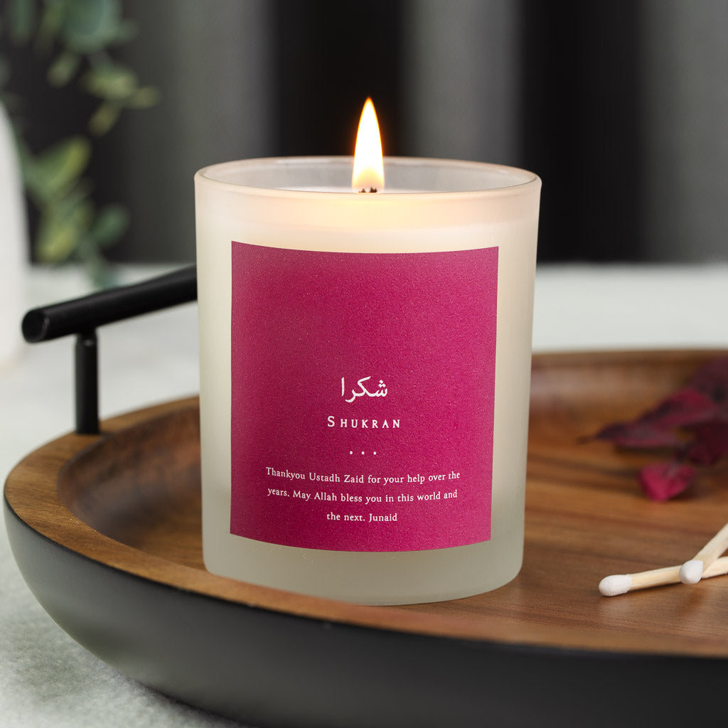 Personalised Islamic teacher candle with Arabic script above white capitals on deep berry
