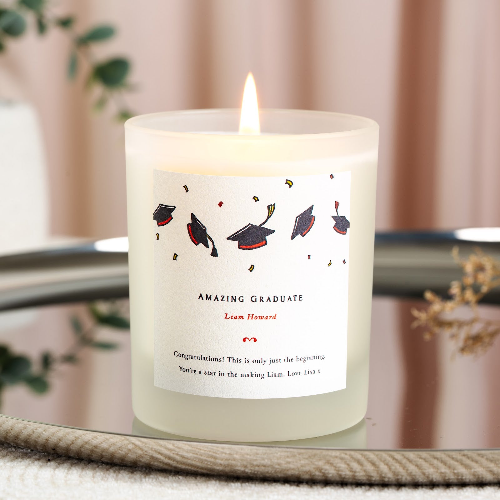 Personalised graduation candle with scattered caps and confetti in navy, red and gold