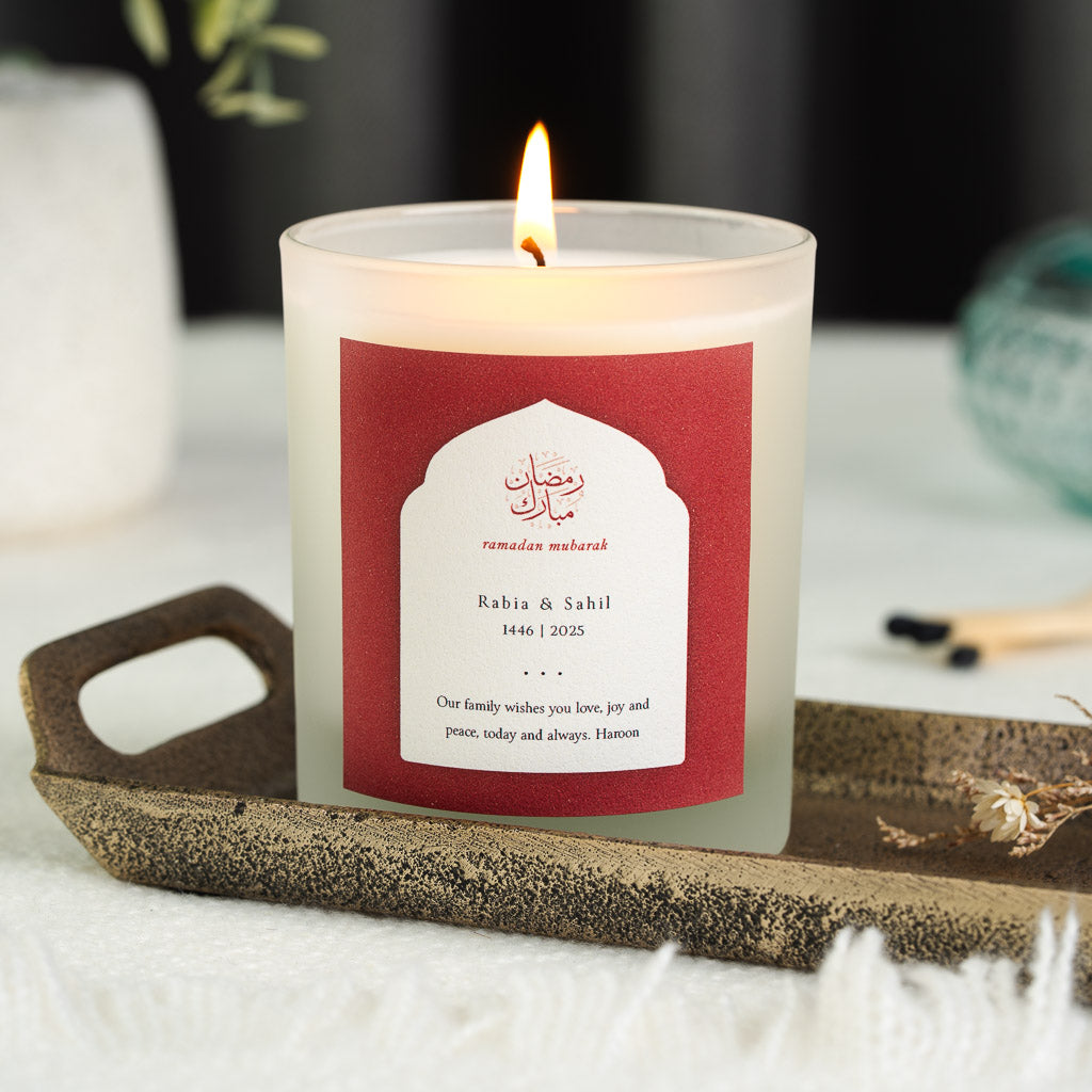 Gold-toned Arabic calligraphy inside a white arch on a crimson personalised Ramadan candle