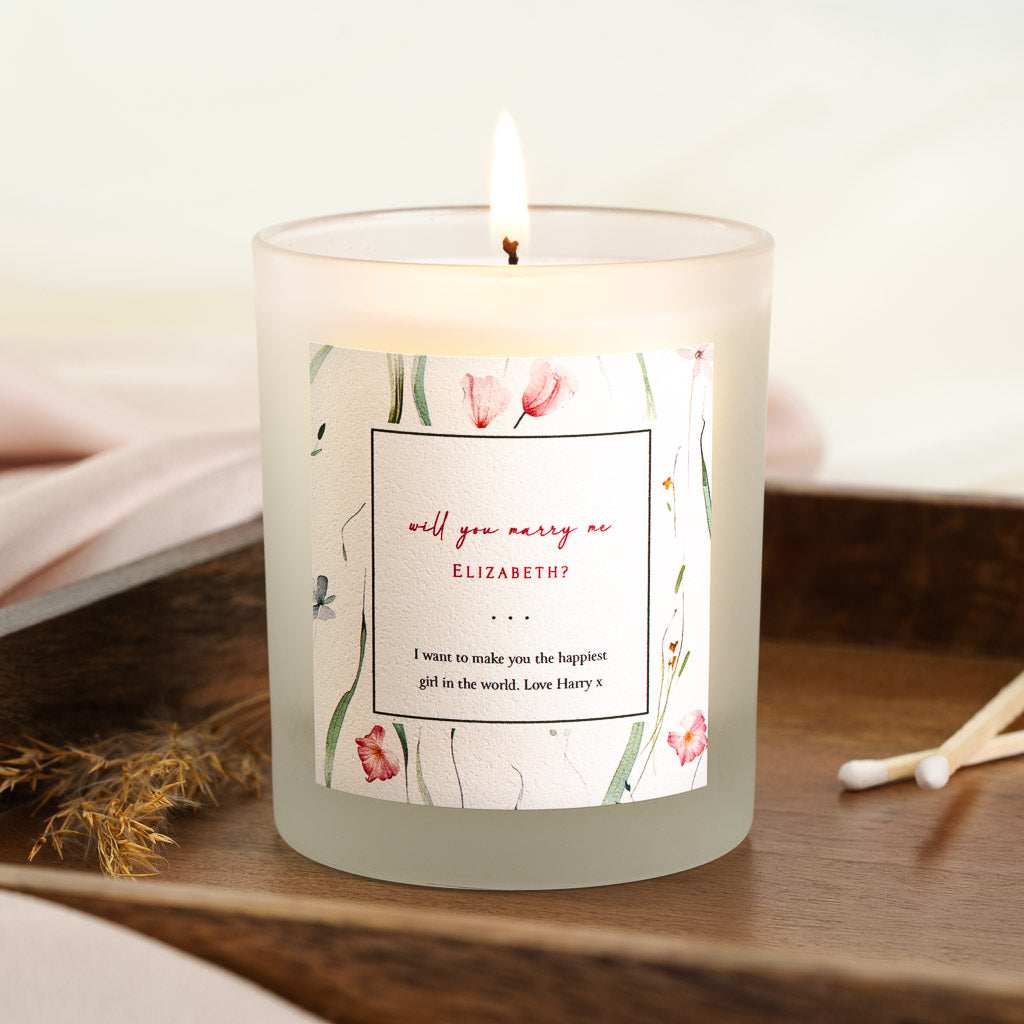 Loose pink, red and blue watercolour flowers around a personalised wedding proposal candle
