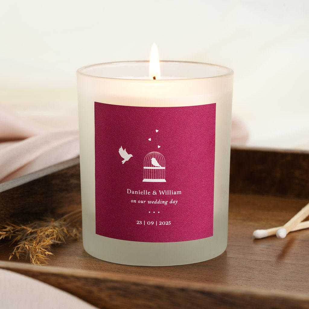 Dove in flight beside an open birdcage on a magenta personalised wedding candle label
