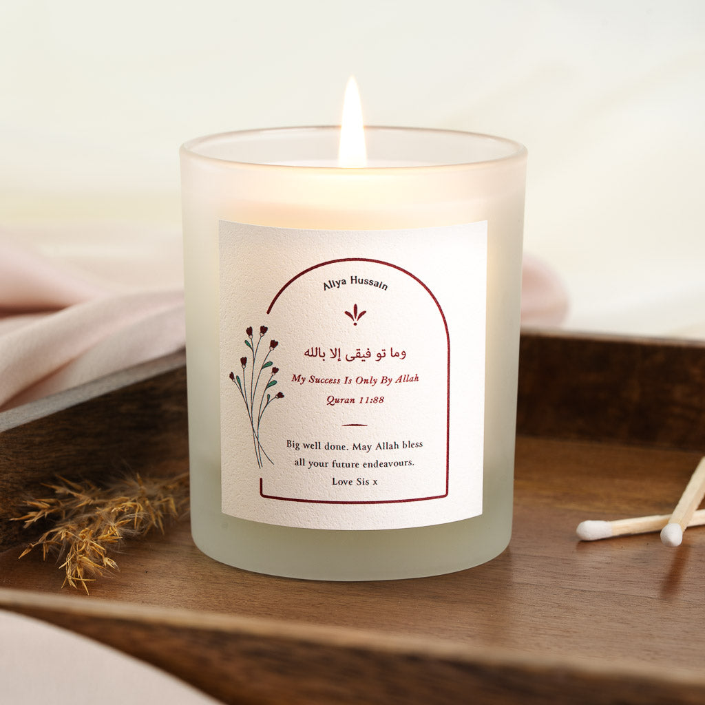 Personalised Islamic graduation candle with rose sprigs beside Surah Hud in an arch
