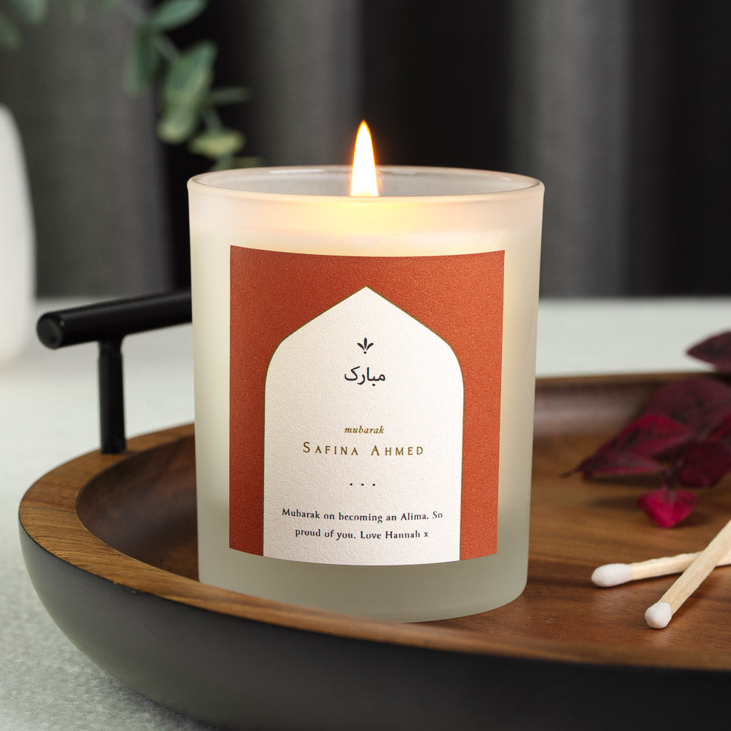 Rust background around a white archway holding Arabic script on a personalised candle
