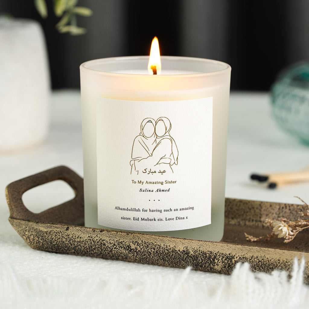 Gold line illustration of two women in hijabs embracing on a personalised Eid candle