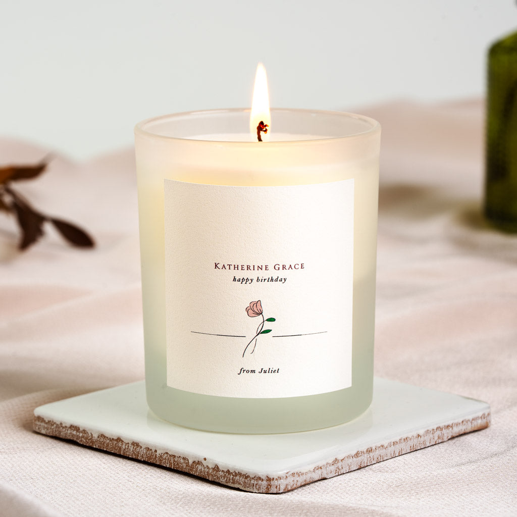 Personalised birthday candle with a rose illustration resting on a fine rule