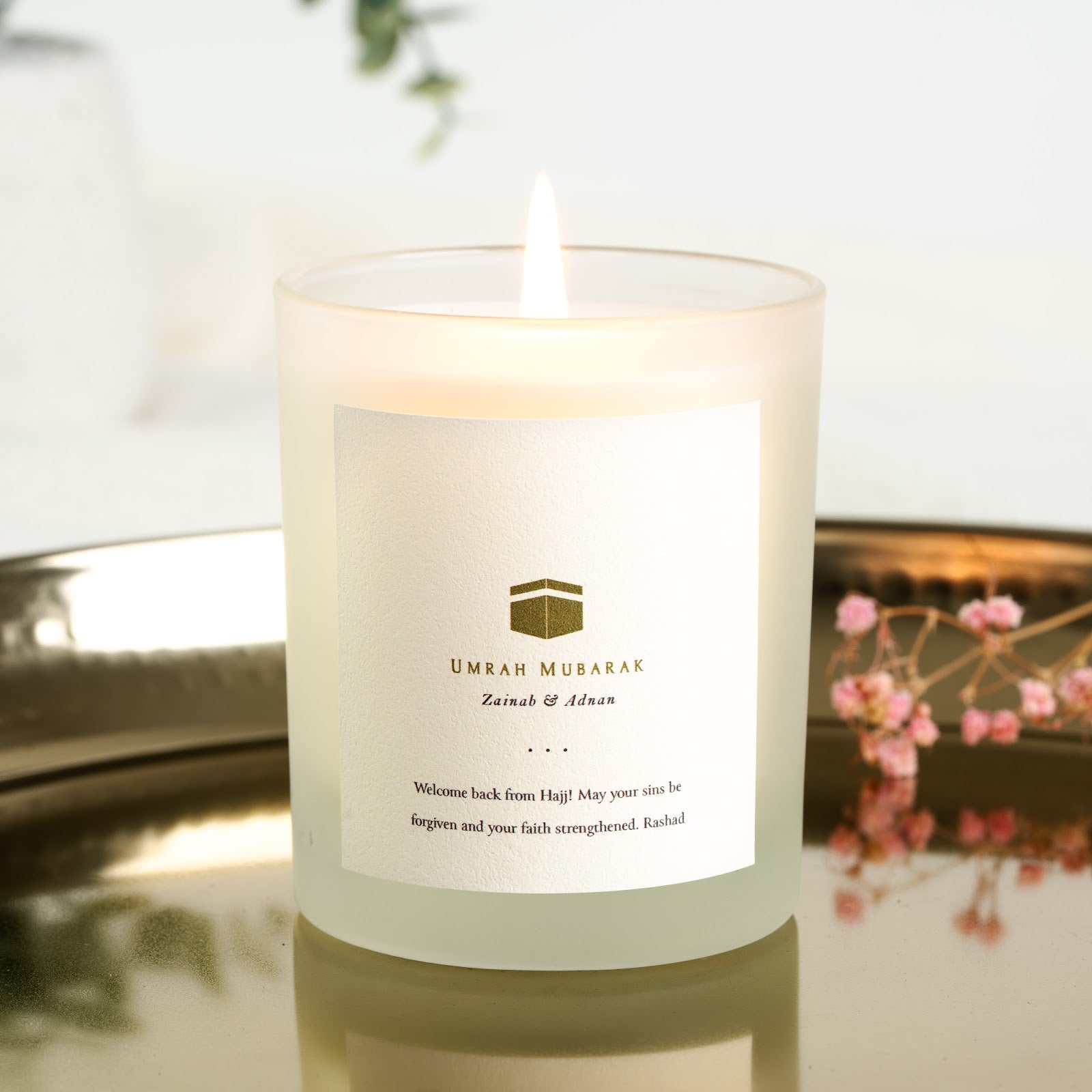 Gold-toned Kaaba icon above the greeting on a personalised Umrah mubarak candle label