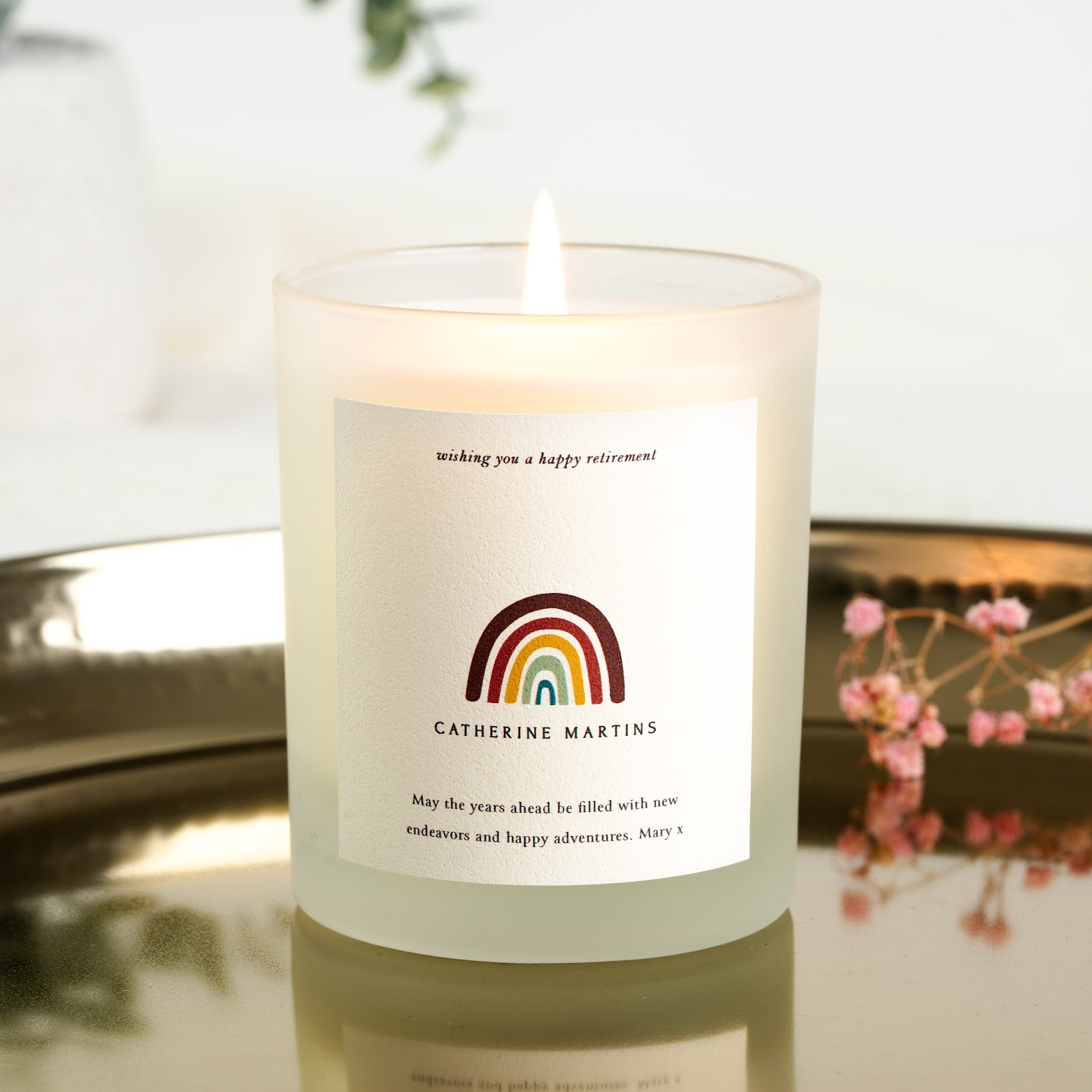 Rainbow illustration beneath a happy retirement line on a personalised candle label