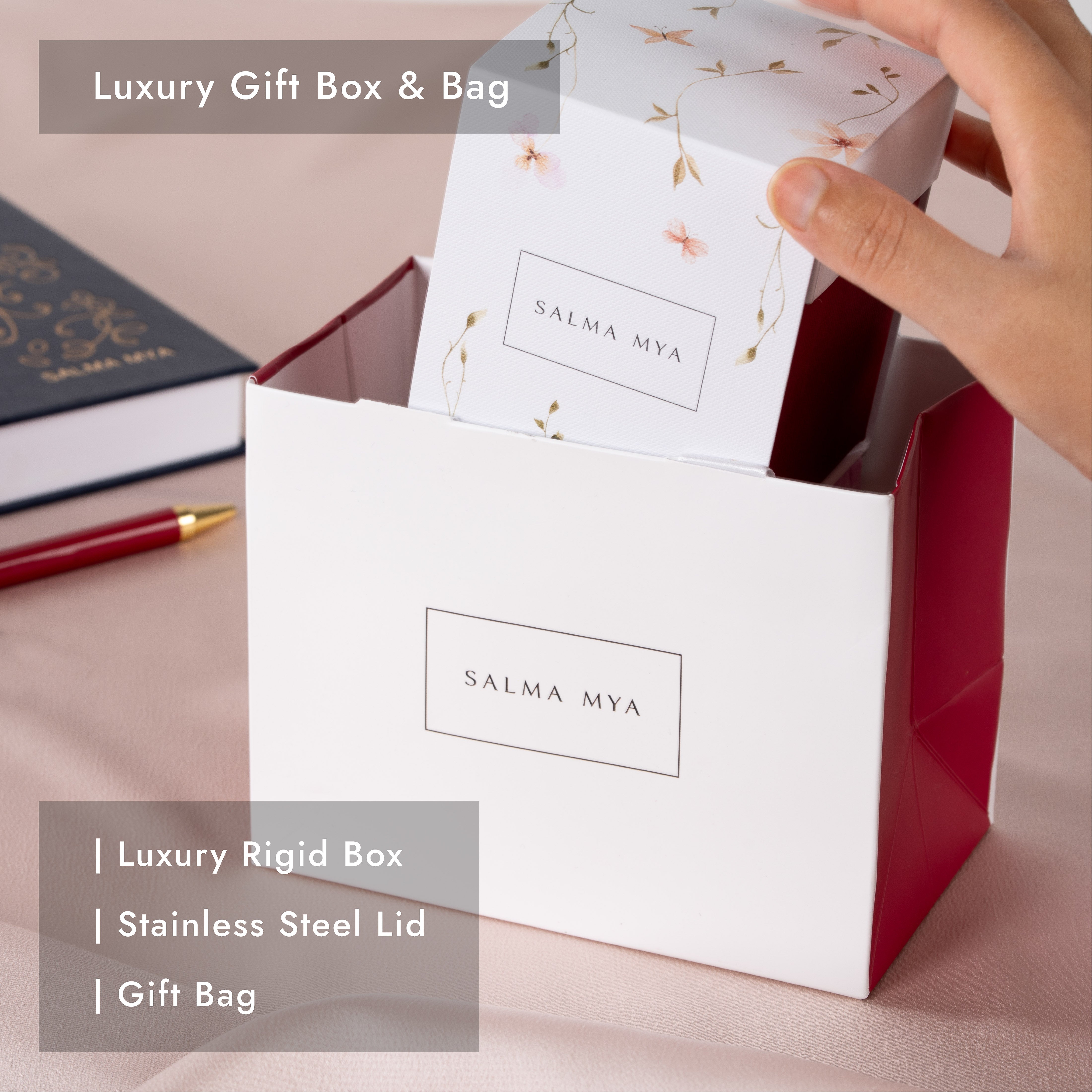 Luxury gift box with floral sleeve being lifted from the matching white and deep red SALMA MYA gift bag