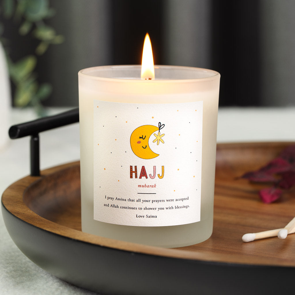 Illustrated moon and star above coloured lettering on a personalised Hajj mubarak candle