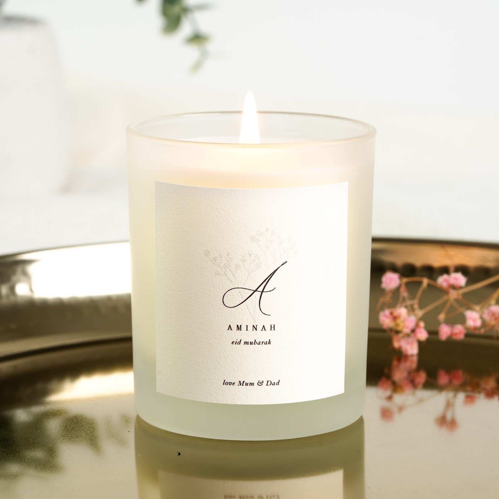 Personalised Eid candle with a large maroon script initial above a faint botanical wreath