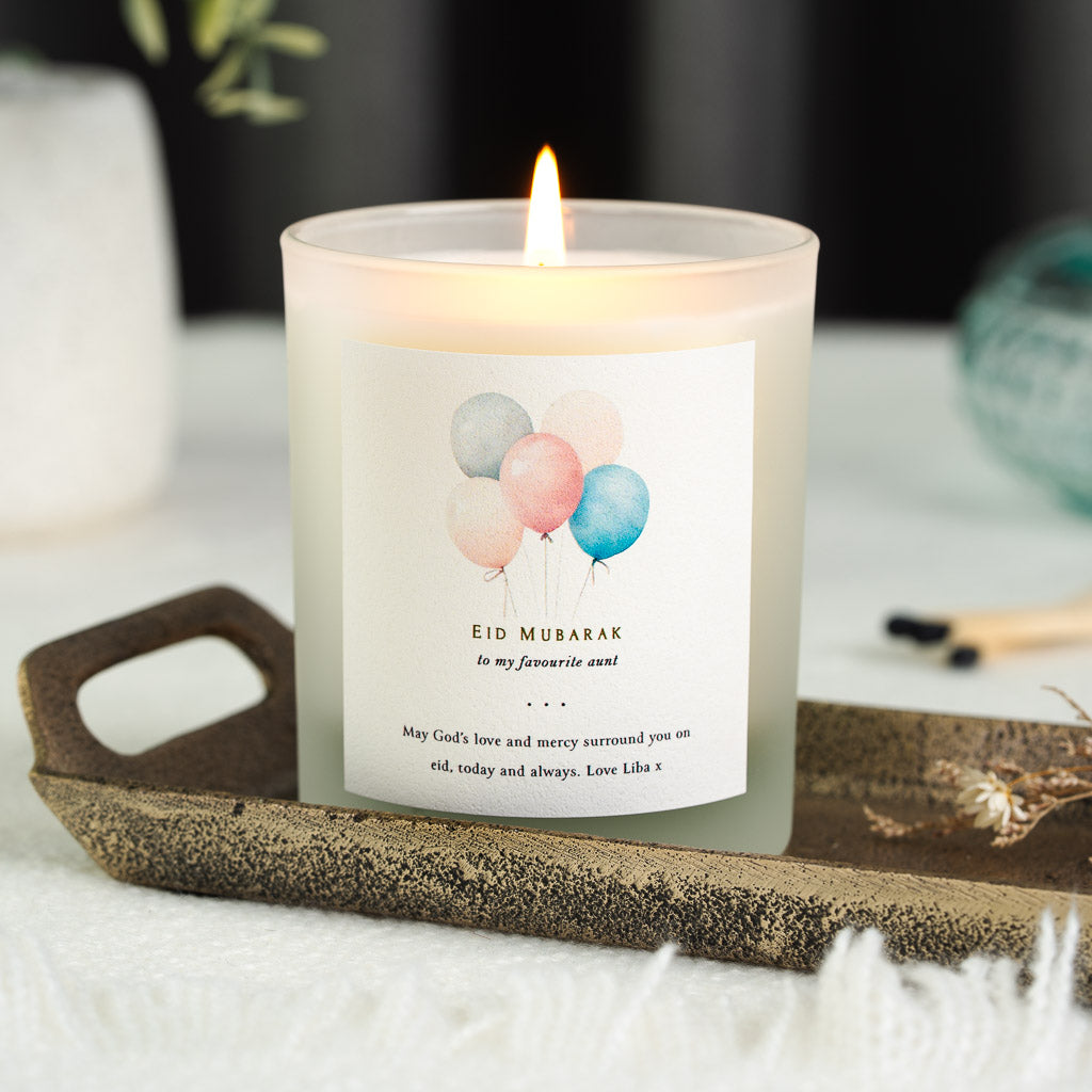 Watercolour balloons in soft grey, pink and blue on a personalised Eid Mubarak candle