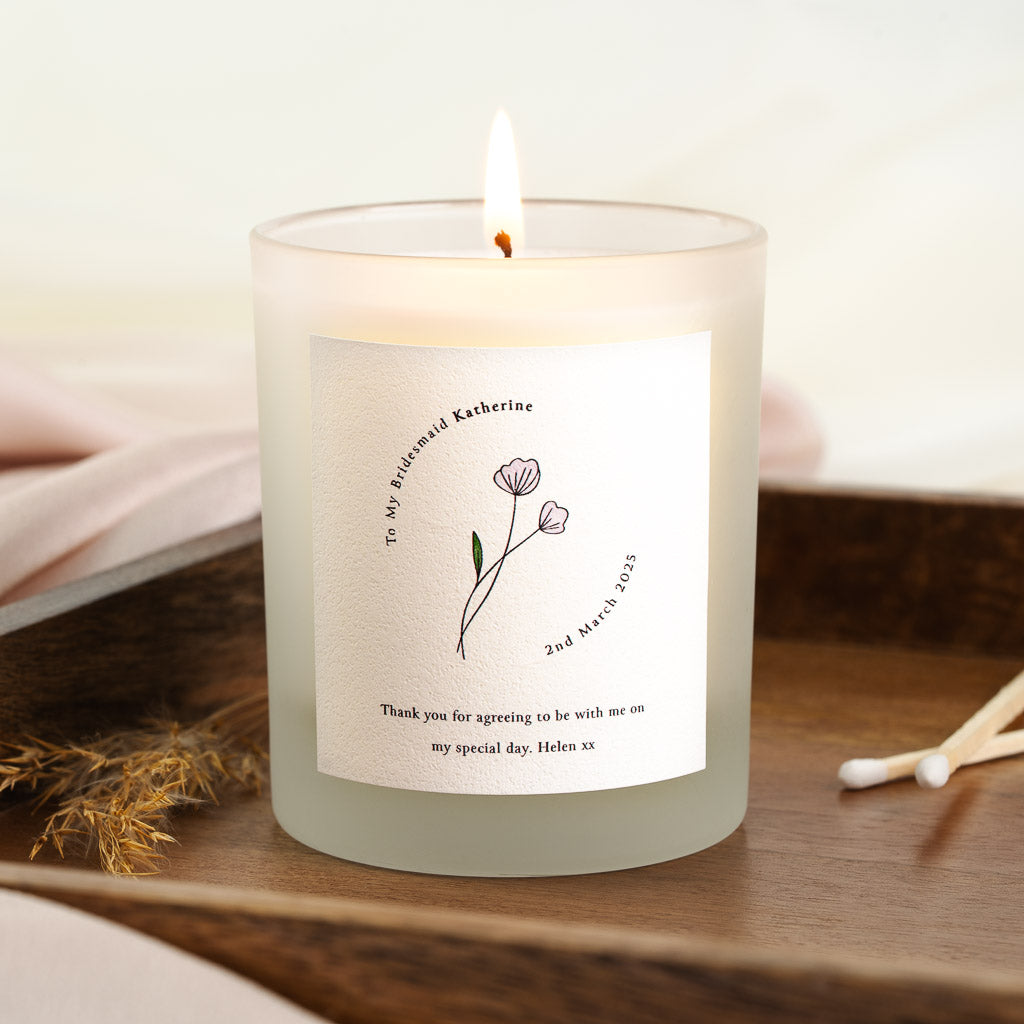 Delicate line-drawn flowers curving beneath arced text on a personalised bridesmaid candle