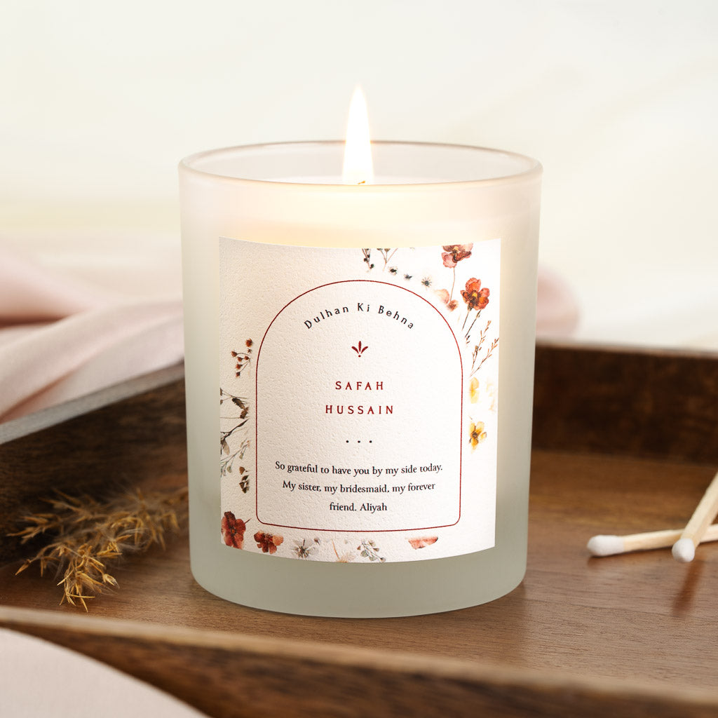 Arched panel bordered in red within scattered pressed florals on a personalised bridesmaid candle