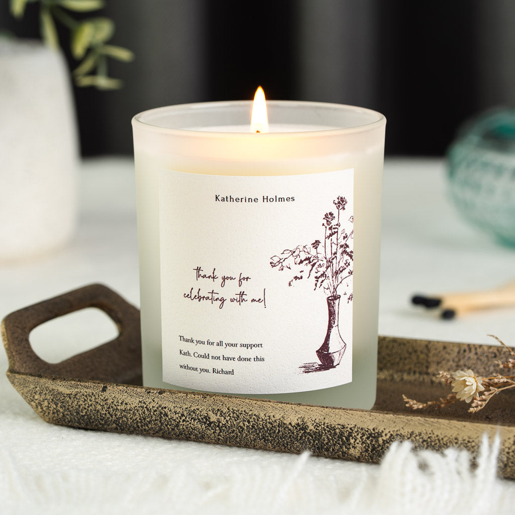 Personalised thank you candle with sketched stems in a vase beside handwritten script in deep plum