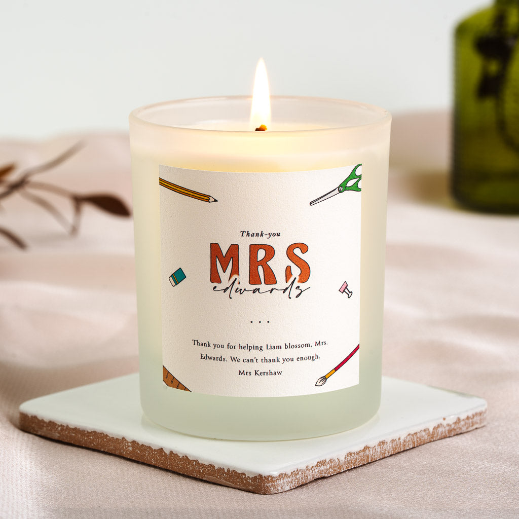 Personalised teacher candle with pencils, scissors and a paintbrush scattered around bold type