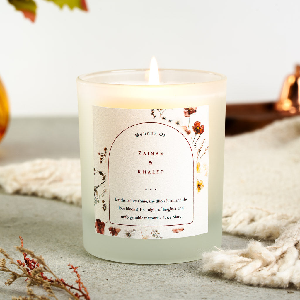 Pressed red and rust florals around a red-outlined arch on a personalised mehndi candle