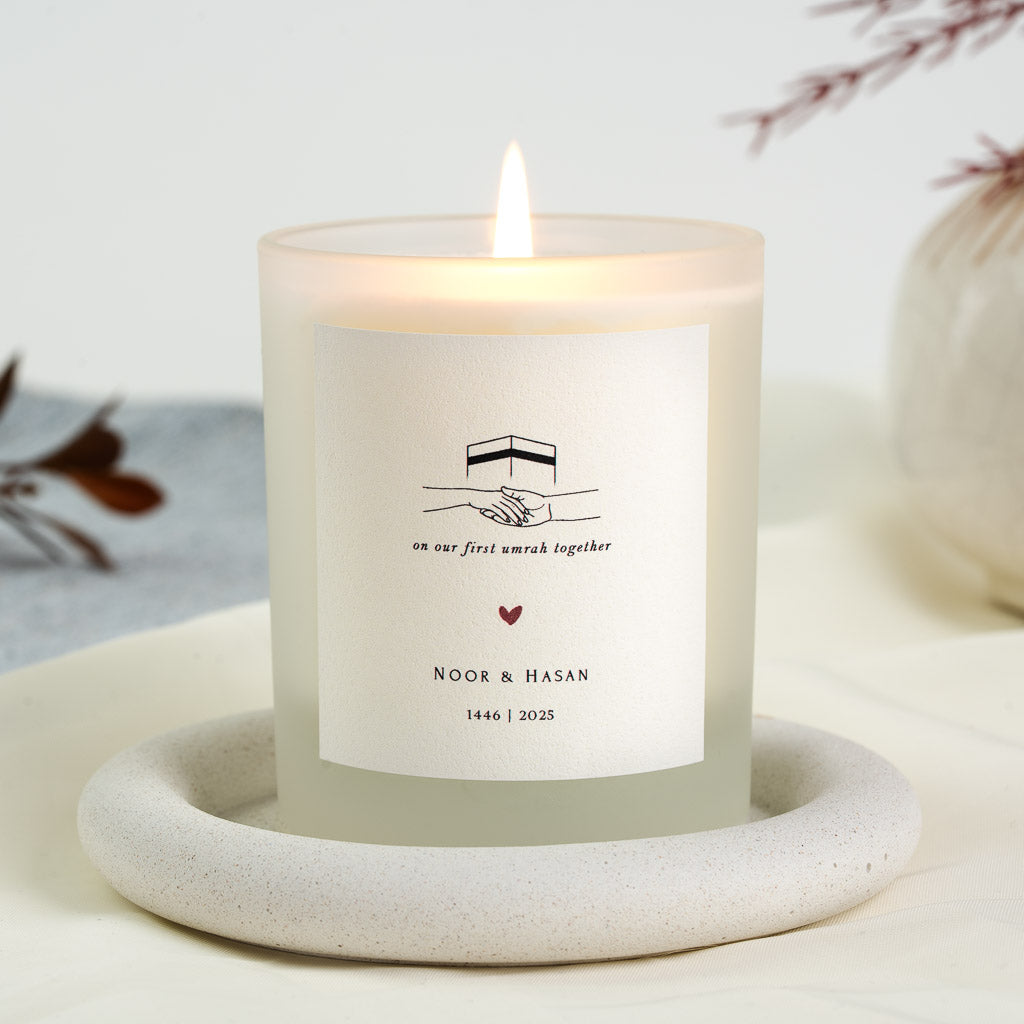 Minimal Kaaba and joined hands above a script message on a personalised Umrah candle
