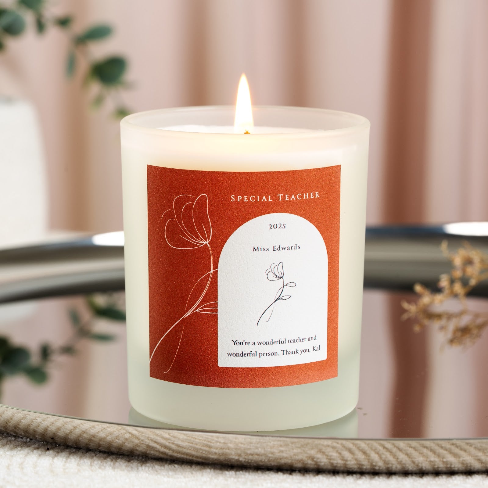 Personalised teacher candle with a fine white line flower on a rust background
