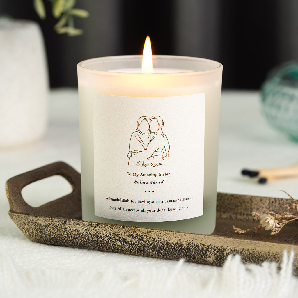 Two embracing figures above Arabic calligraphy on a personalised Umrah candle label