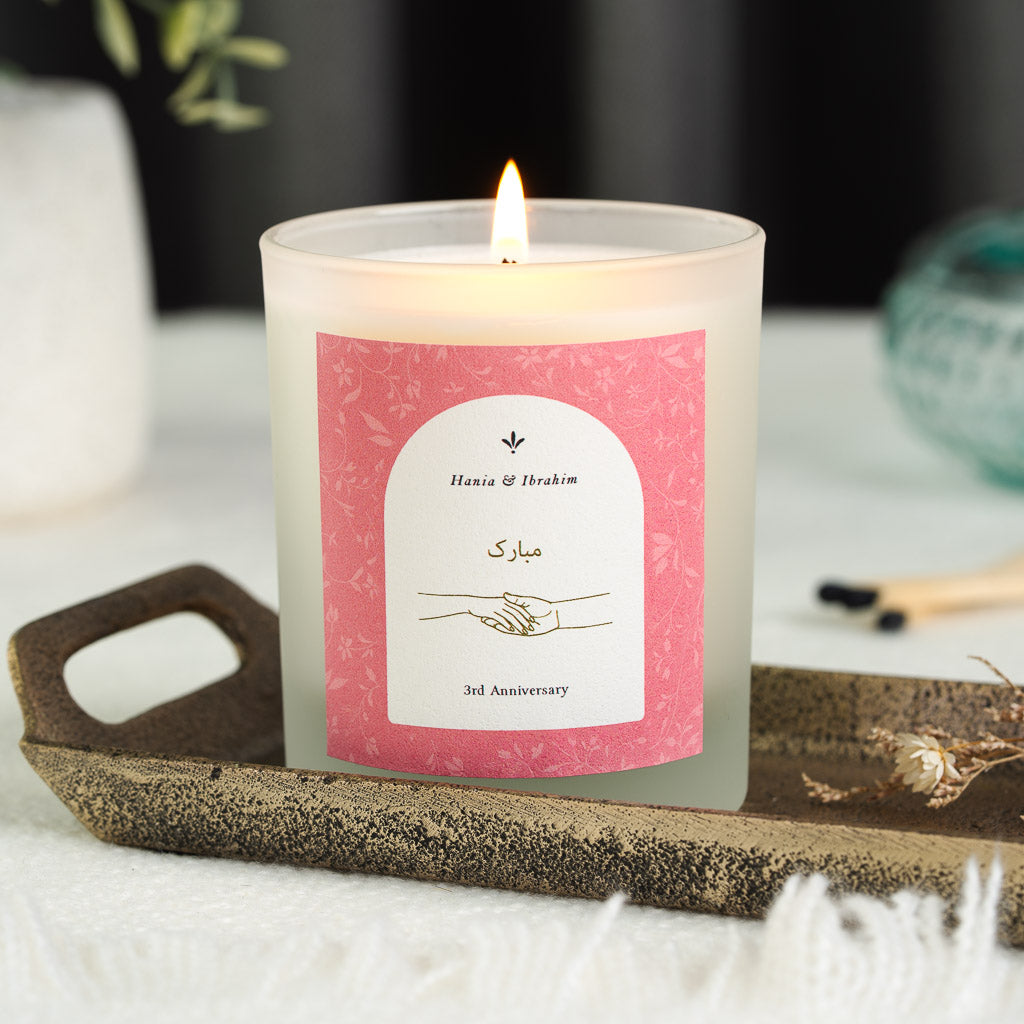 White arch on a pink floral panel holding gold script on a personalised anniversary candle