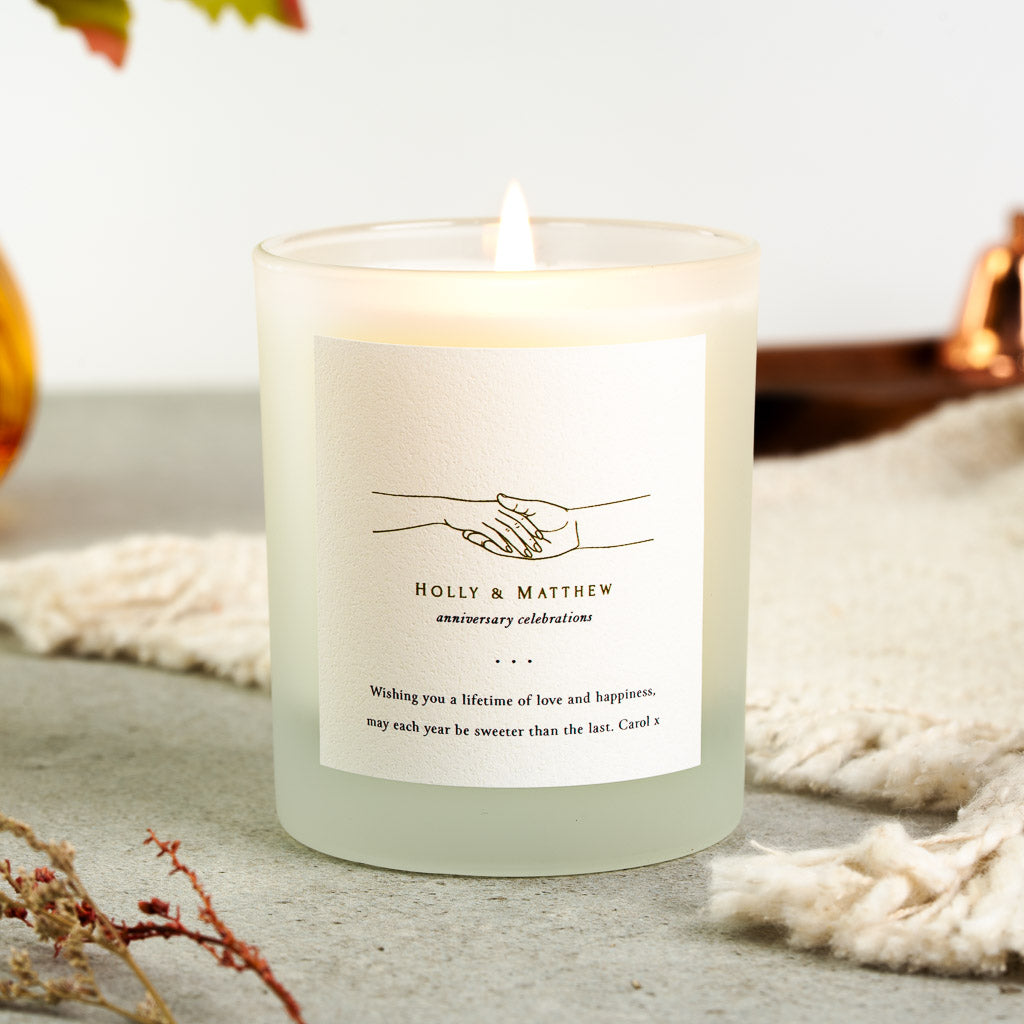 Personalised anniversary candle with a clasped hands illustration above a short phrase