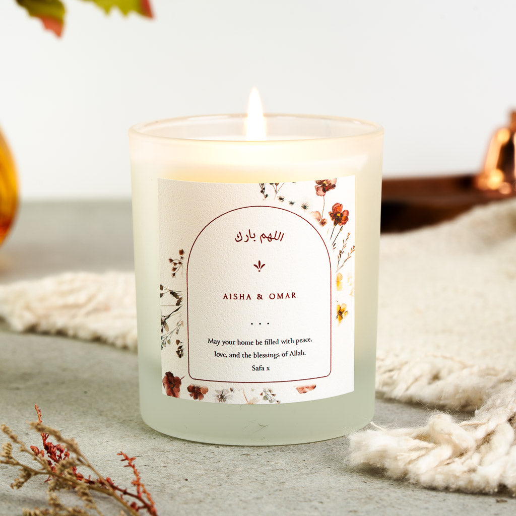 Arch outline bordered by red and amber wildflowers on a personalised Islamic home candle