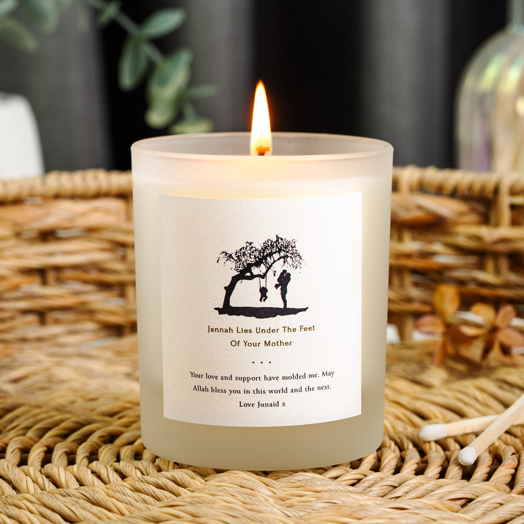 Black silhouette of a parent and child beneath a tree branch on a personalised candle