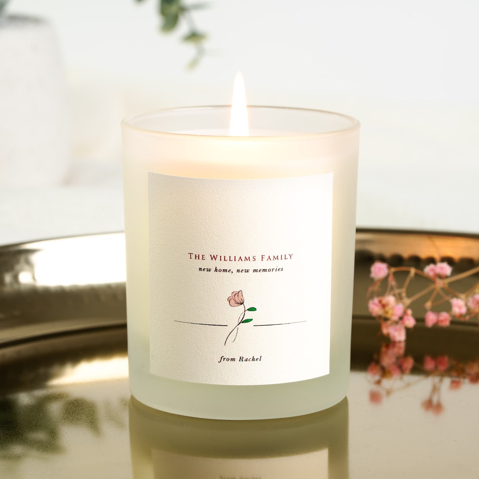Personalised new home candle with a flower illustration beneath the family name in deep red
