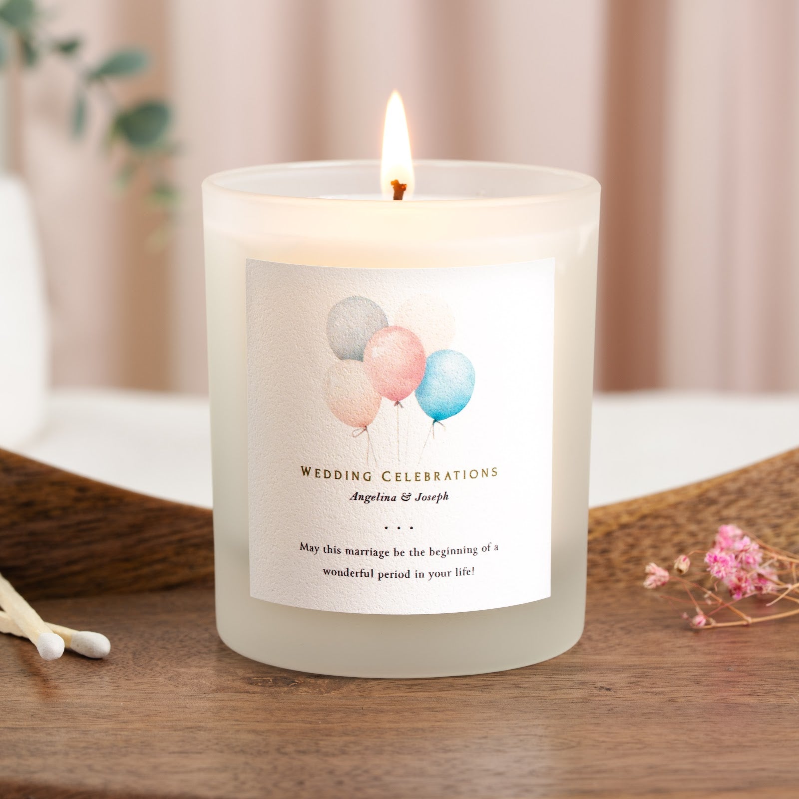 Watercolour pastel balloons above gold-toned lettering on a personalised wedding candle
