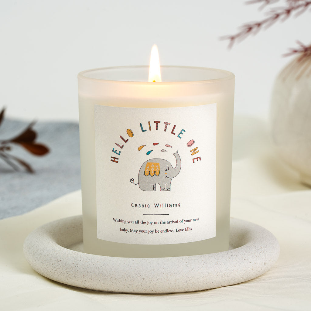 Grey elephant beneath arched multicoloured lettering on a personalised new baby candle label