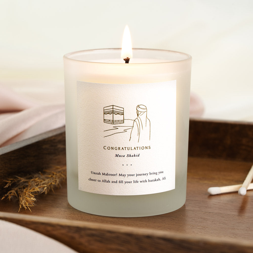Gold line drawing above congratulations in capitals on a personalised Umrah candle label